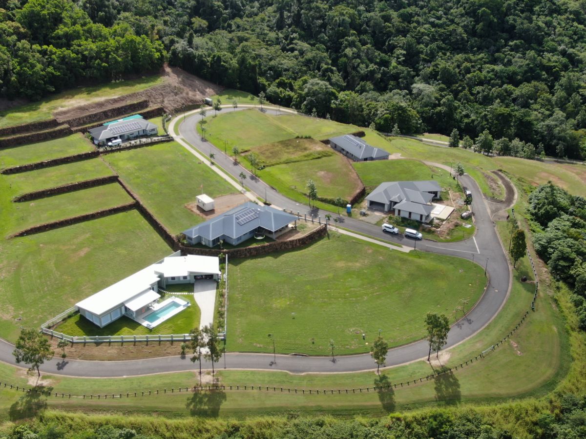 Aerial view of new homes and grassed building lots on a terraced hillside at Red Peak Forest Estate